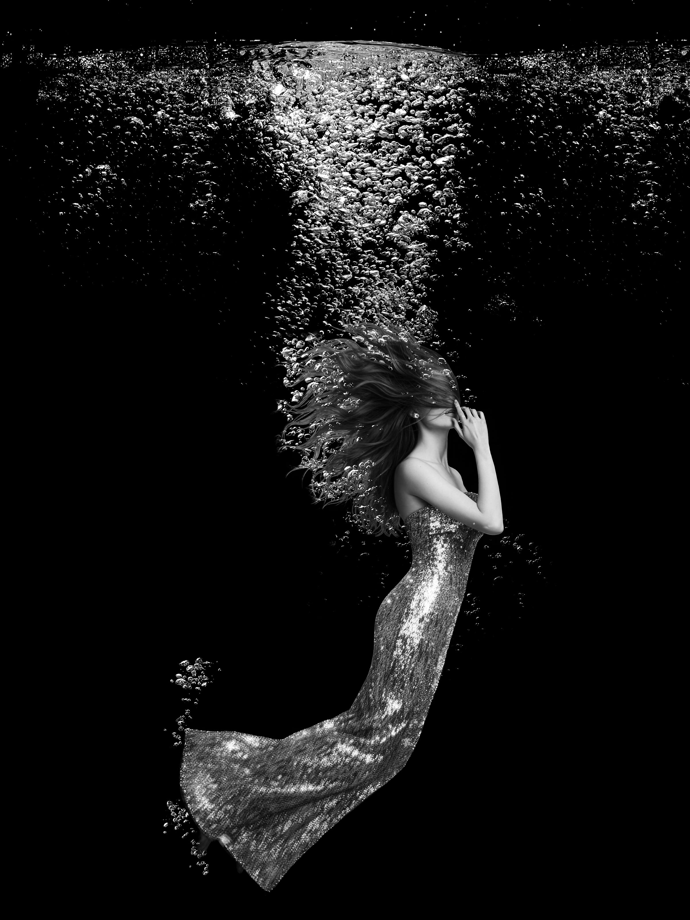 Woman in a sparkling dress underwater with bubbles